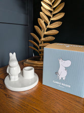 Load image into Gallery viewer, Ceramic Moomintroll candle holder glowing warmly with a lit tealight, white rounded figure with black line detail, lifestyle setting