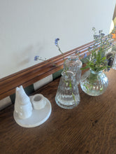 Load image into Gallery viewer, A set of three ribbed glass vases of different shapes and sizes, one containing water with small blue flowers, arranged on a wooden table next to a white ceramic gnome figurine.
